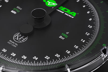 Macro of the dial centre showing the twin needles, the Reuben Heaton RH roundel and the 100g / 2oz graduation marking