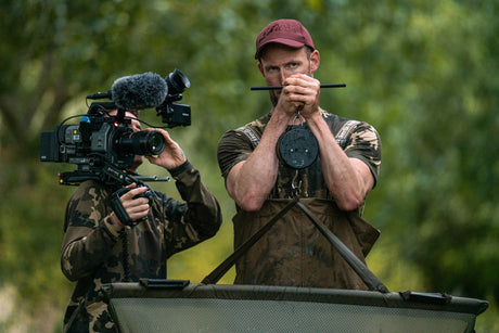The scale in use on the bank, taking the weight of a loaded weigh sling while a cameraman films the capture