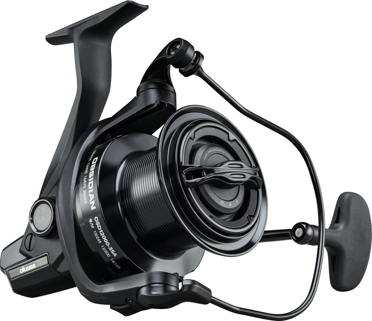 Handle side of the Obsidian OSD12000-35A with the okuma badge on the body, screw-in handle and the spool's imperial capacity ring