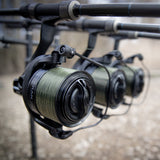 Three Obsidian big-pit reels loaded with green mono, mounted on carp rods sat on a rod pod at the bank