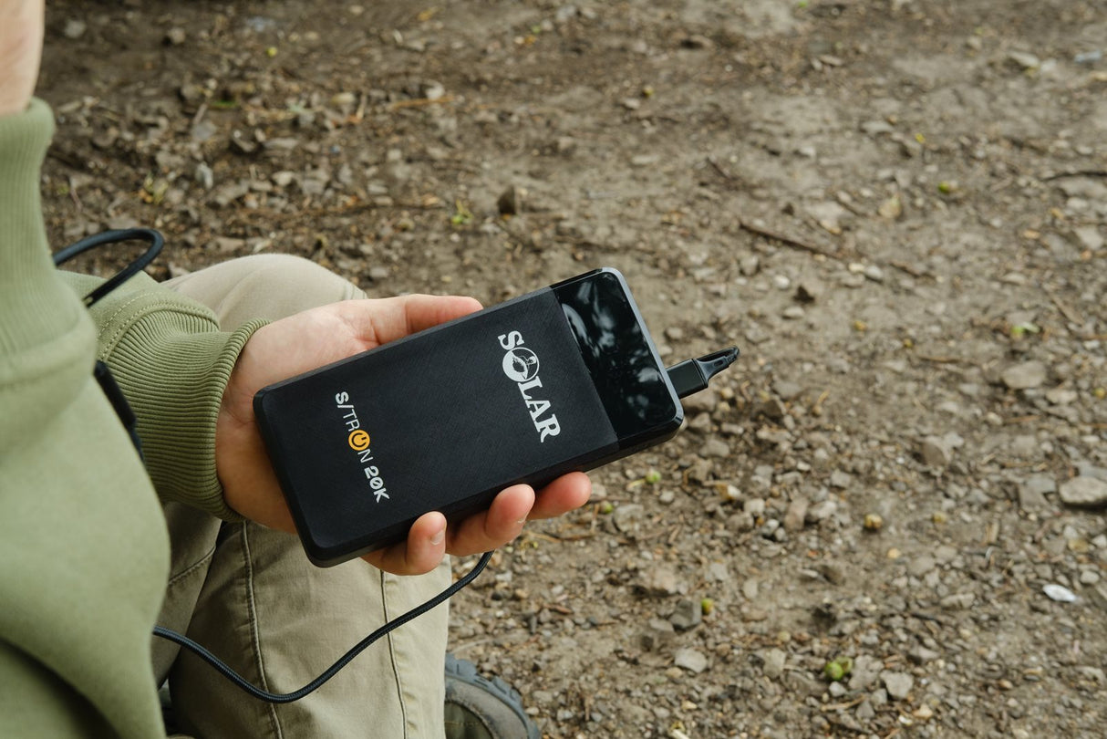 Solar S-Tron 20K pocket powerpack held in one hand with a cable plugged in