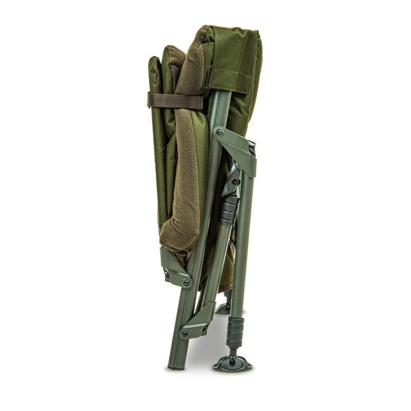 The chair folded and stood on end, held closed by the leglock buckle strap - shows the packed size claim. Fleece arm roll and one mud foot visible.