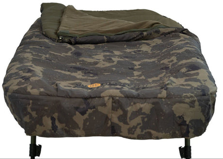 End-on view from the foot of the bed with the bag turned back, showing the Worldwide camo peach skin mattress outer, the gold oval badge and the leg tops.